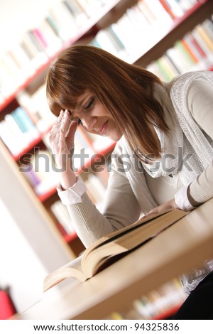 Portrait of troubled girl touching head while preparing for seminar in college library