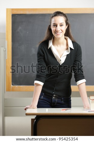 Portrait of a young woman, teacher in front of a blackboard