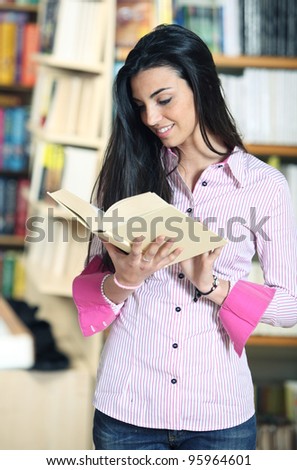 smiling female student with book in hands in a bookstore