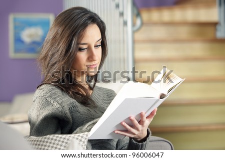 Portrait of a young woman lying on couch with book