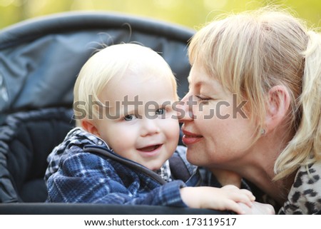 Happy moments: little boy in stroller with mother on outdoor walk.
