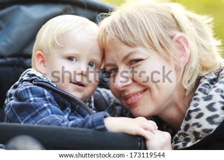 Happy moments: little boy in stroller with mother on outdoor walk.