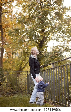 Happy moments: little boy with mother on outdoor walk in autumn park.