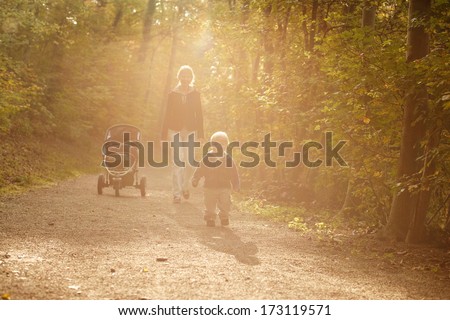 Little boy with mother on outdoor walk in autumn park.