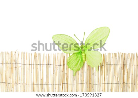 Big green paper butterfly on straw fence.