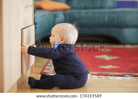 Little boy trying to open and look inside drawer chest.