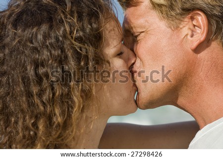 Real kiss. Real love. Romantic couple on the blue Caribbean sky background.