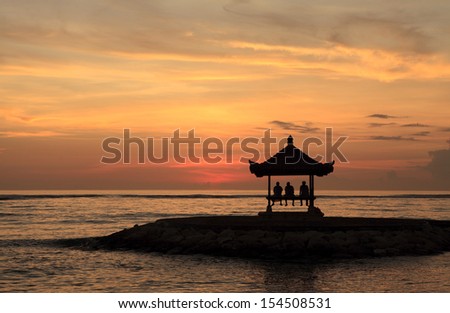 A pagoda on Sanur Beach, Bali, at dawn. There are threee people waiting to see the sun rise.