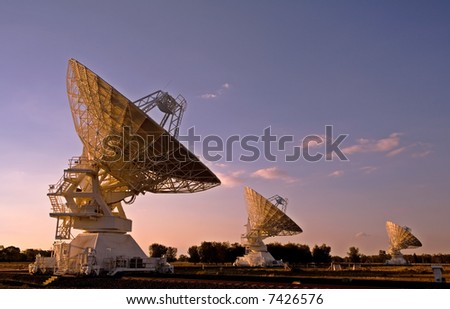 three radio telescopes photographed at sunset