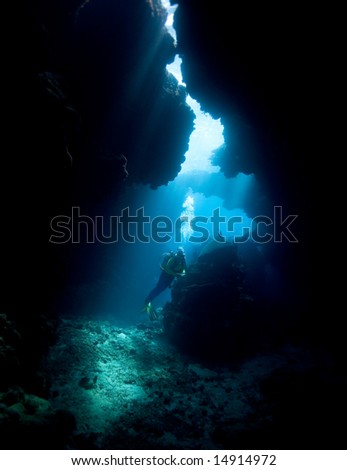 a female scuba diver in an underwater cave with sunbeams