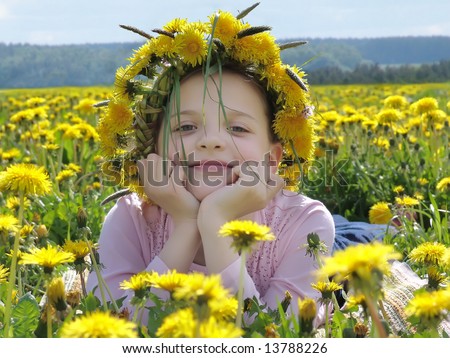 Young happy girl with wreath of flowers among the field in bloom