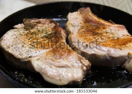 pork meat with rosemary on a cast iron skillet