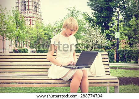 beautiful girl in the garden on a sunny day at work with a laptop