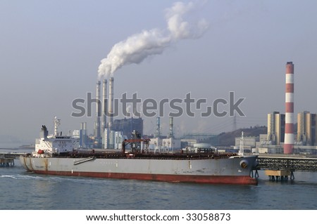 Chemical/power plant air pollutions with white clouds of smoke, crude oil tanker, disharging on front