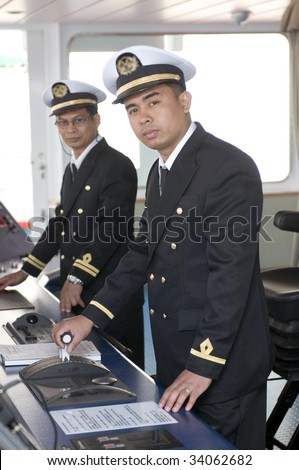 Navigation officers manage devices, looking ahead on the navigation bridge of ocean ship
