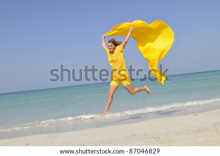 An active caucasian white fitness woman in yellow clothes running on the sand of the beach