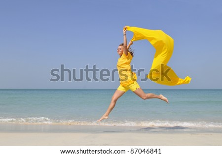 An active caucasian white fitness woman in yellow clothes running on the sand of the beach