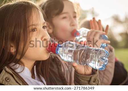 Photo of two girls drinking water from the PET bottle