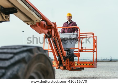 Operator In Safety Helmet and red square shirt controlling Straight Boom Lift