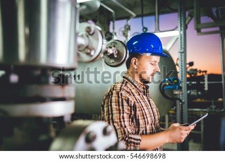 Man wearing blue hardhat using tablet at Natural gas processing facility