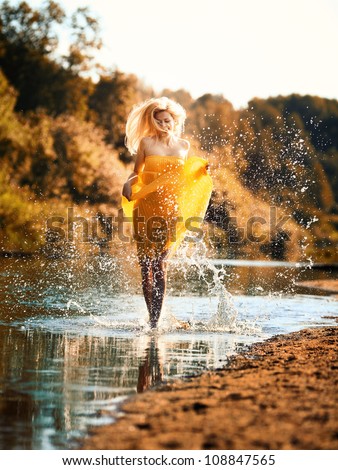 beautiful young woman sprinkles water in the river