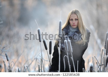 Russian blonde with beautiful long hair, freezing in winter fur coat and gloves