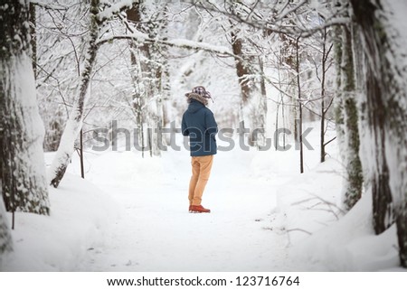 A young man in a winter forest, seen from behind