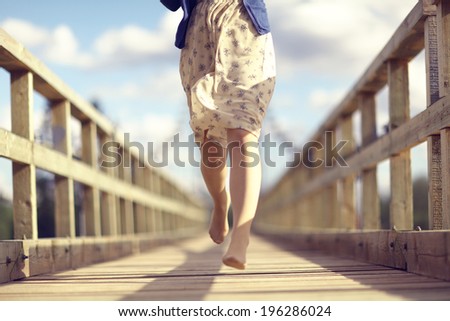 happy girl dress runs over the bridge