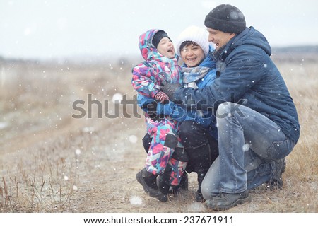 young family with a child playing on winter field