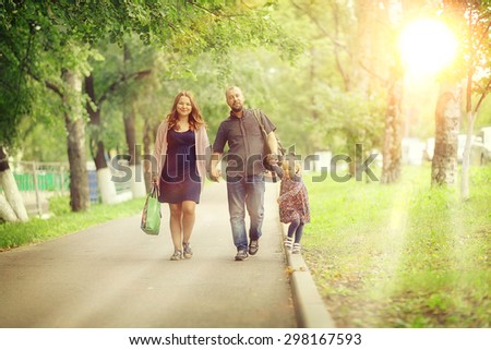 Mom and young daughter and dad, a young family on a walk in the park in summer