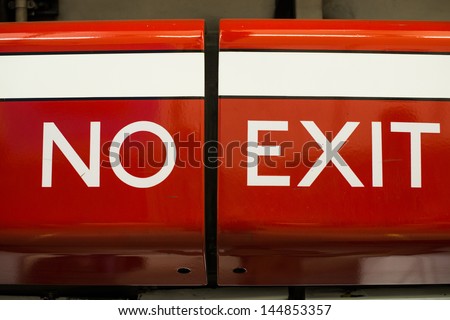 No Exit sign on a red metal barrier preventing somebody from leaving by that route