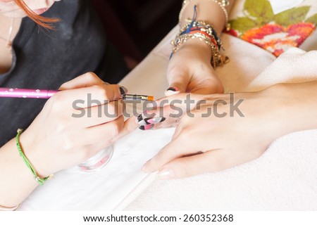 manicurist applying liquid acrylic to nail extensions