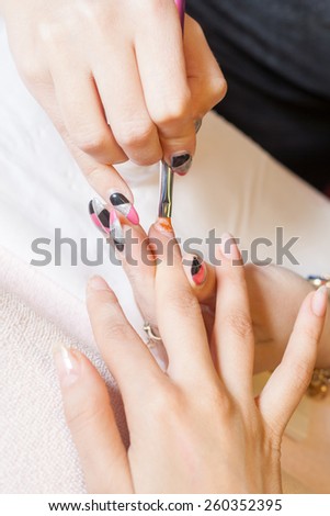 Professional manicurist applying liquid acrylic to nail extensions