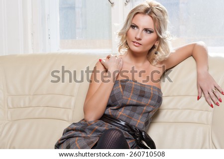 Beautiful blonde woman sitting on a leather couch