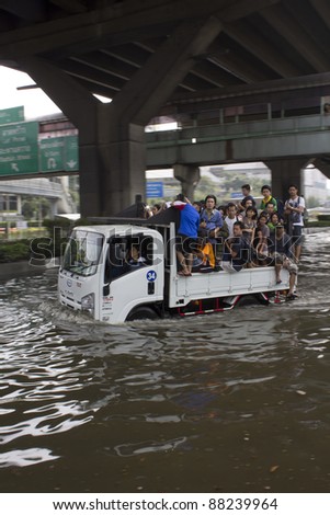 BANGKOK-NOV 5: Unidentified people sit and stand in big truck to escape rising flood waters at Vipavadeerangsit Road, in Bangkok, Thailand on November 5, 2011