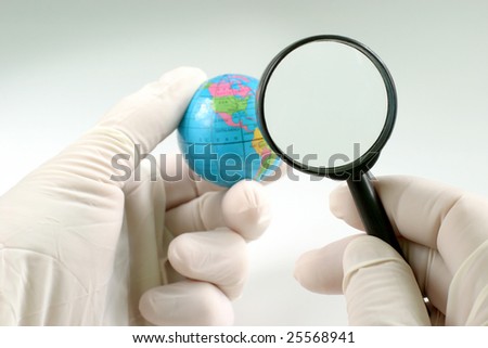 Earth globe & human hand with magnifying glass