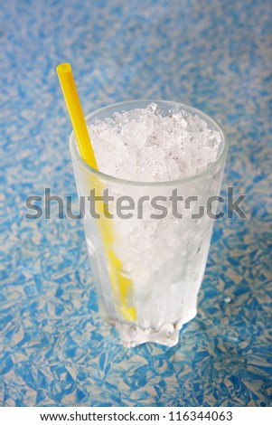 Glass of ice with plastic tube on blue and white  background