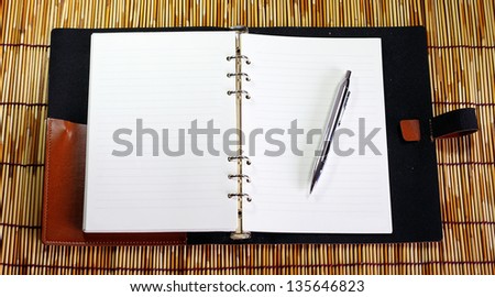 Notebook and silver pen on bamboo background.