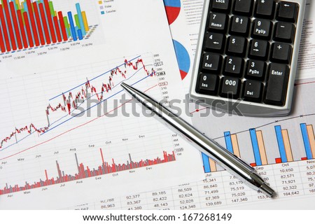 Business finance chart with number pad and silver pen on table.