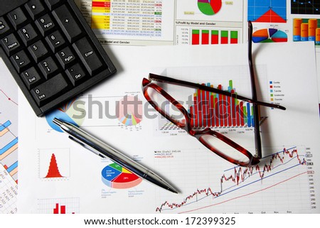 Glasses, numeric pad and silver pen on business finance chart