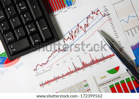 Business finance chart with number pad and silver pen on table.