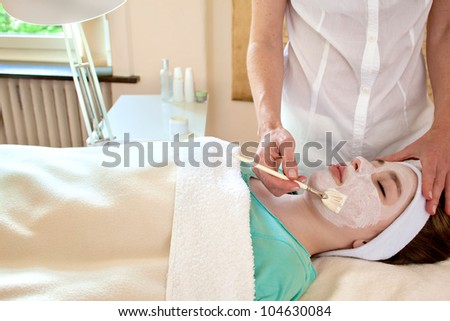 Alternative practitioner applying a chemical peel to a female patient\'s face in a beauty clinic