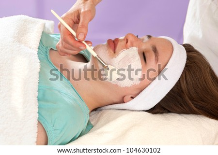 Alternative practitioner performing a chemical face peel on a young female patient