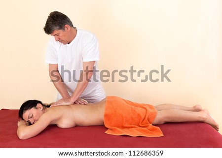 Physical therapist giving a young woman a back massage in a health center