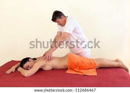 Physical therapist giving a young woman a back massage in a health center