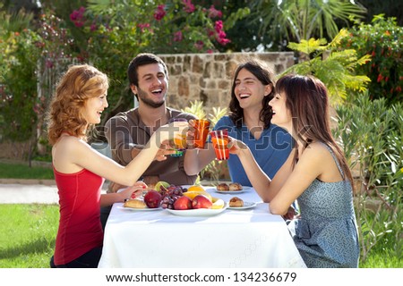 Two couples celebrating. Two couples celebrating seated around a table in a lush garden having a meal laughing and toasting each other with their drinks