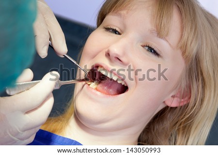Woman having teeth examined by a Dental-Surgeon. Close-up of a beautiful blond woman having the back teeth examined by a Dental-Surgeon using medical tools