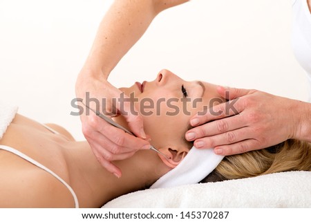 Homeopath using ear acupuncture techniques. Alternative practitioner using ear acupuncture techniques  also called auriculotherapy  on the ear of a beautiful blond woman