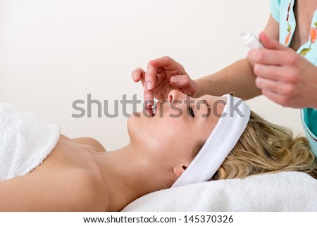 Beautician applying balm on the lips of a woman. Beautician applying balm on the lips of a relaxed beautiful blond woman