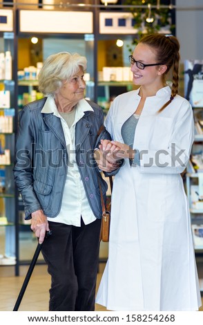 Young female pharmacist gently holding and supporting senior female patient in the pharmacy